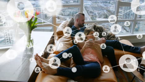 Animation-of-network-of-connections-with-people-icons-over-caucasian-couple-using-smartphones
