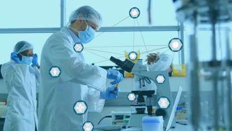 Animation-of-network-of-medical-icons-over-diverse-scientists-working-at-laboratory