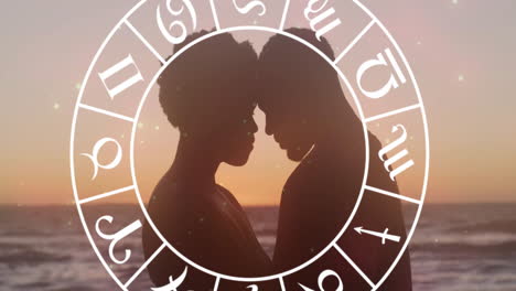 Animation-of-horoscope-moving-over-happy-biracial-couple-embracing-at-beach
