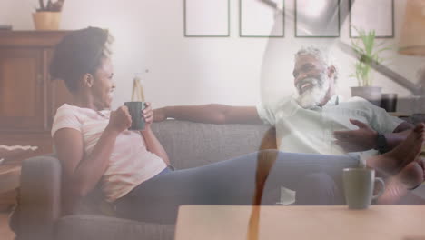 Animation-of-coffee-over-african-american-couple-sitting-on-sofa,-slow-motion