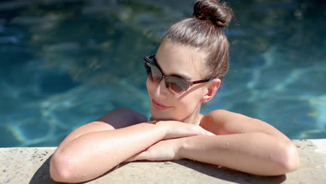 Teenager-Mädchen-Genießt-Den-Pool,-Ihr-Haar-Zu-Einem-Knoten-Gebunden-Und-Sonnenbrille-Auf