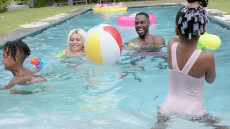 Happy-family-of-an-African-American-man-and-young-biracial-woman-splash-in-a-pool-with-two-children