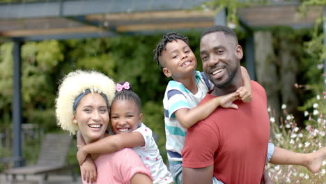 African-American-man,-young-biracial-woman,-and-two-children-smile-outdoors