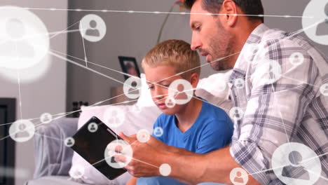 Animation-of-network-of-connections-with-icons-over-caucasian-father-with-son-using-tablet