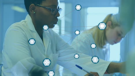 Animation-of-network-of-medical-icons-over-diverse-female-scientists-working-at-laboratory