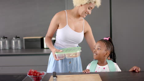 Biracial-mom-and-daughter-share-a-moment-in-kitchen-with-fruit.