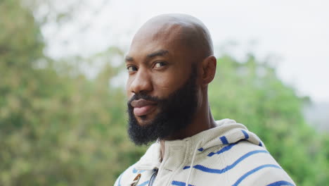 African-American-man-with-beard-looking-at-camera-outdoors,-wearing-a-striped-hoodie