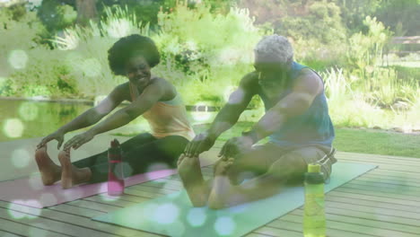 Animation-of-light-spots-over-african-american-couple-doing-yoga,-stretching,-slow-motion