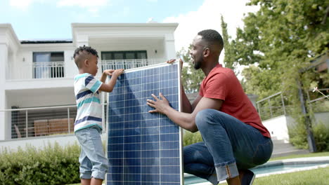 African-American-man-and-his-son-install-a-solar-panel-outdoors-at-home
