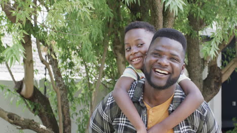 Afroamerikanischer-Vater-Mit-Einem-Strahlenden-Lächeln-Trägt-Einen-Fröhlichen-Sohn-Auf-Dem-Rücken
