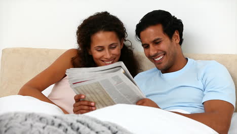 Couple-in-the-bed-reading-a-newspaper-