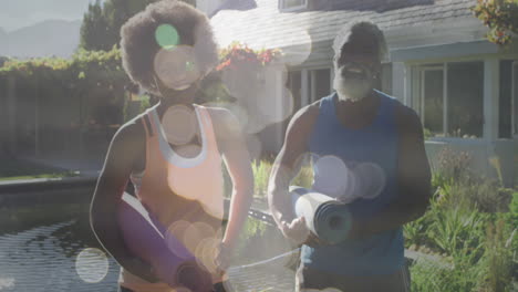 Animation-Von-Lichtpunkten-über-Einem-Afroamerikanischen-Paar,-Das-Yogamatten-Hält,-Zeitlupe