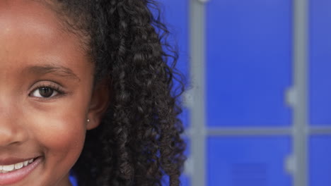 Close-up-of-a-biracial-girl-with-curly-hair-and-a-bright-smile,-with-copy-space,-in-school