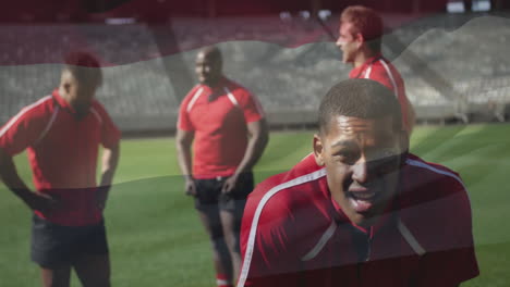 Animation-of-flag-of-hungary-over-tired-african-american-rugby-player-on-pitch-with-teammates