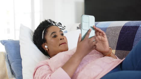 African-American-woman-enjoys-music-while-relaxing-on-a-couch-at-home