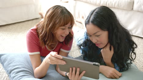 Two-young-biracial-female-friends-are-sharing-a-joyful-moment-with-a-tablet