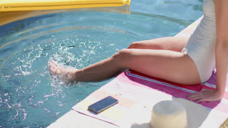 Una-Adolescente-Sumerge-Sus-Pies-En-Una-Piscina,-Creando-Ondas-En-El-Agua