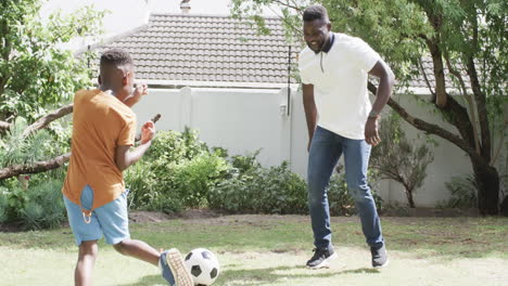 African-American-father-plays-soccer-with-a-son-in-a-sunny-backyard