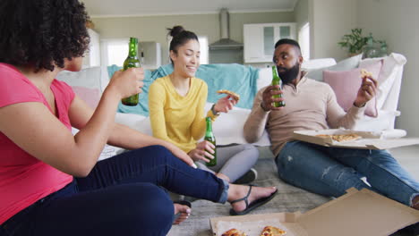 Three-diverse,-happy-female-and-male-friends-talking,-with-beer-and-pizza-at-home,-in-slow-motion