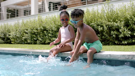 Afroamerikanische-Schwester-Und-Bruder-Genießen-Spaß-Am-Pool-Zu-Hause,-Spritzwasser-Mit-Den-Füßen