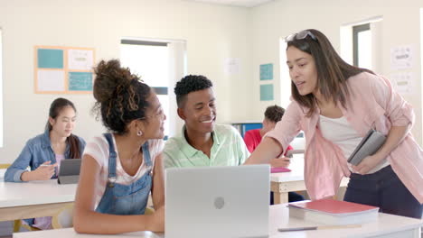 Verschiedene-Teenager-Versammeln-Sich-Um-Einen-Laptop-In-Einem-Hellen-Klassenzimmer