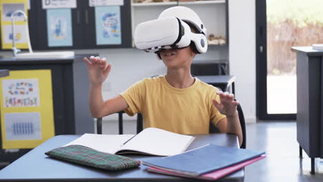 Un-Niño-Birracial-Con-Auriculares-VR-Está-Sentado-En-Un-Escritorio-Con-Cuadernos-En-Un-Aula-De-La-Escuela