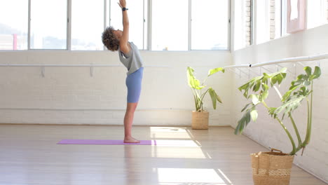 Biracial-young-woman-stretching-in-yoga-studio