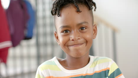 Afroamerikanischer-Junge-Mit-Einem-Fröhlichen-Lächeln,-Der-Zu-Hause-Ein-Gestreiftes-Hemd-Trägt