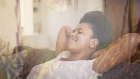 Animation-of-grass-over-african-american-woman-relaxing-on-sofa