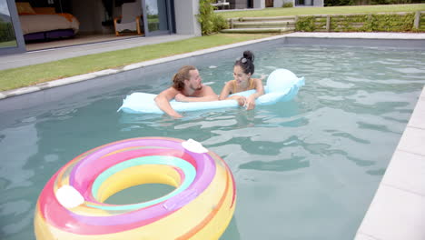A-young-Caucasian-couple-enjoys-a-playful-moment-in-a-pool,-copy-space