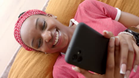 A-young-African-American-woman-lying-down,-holding-smartphone