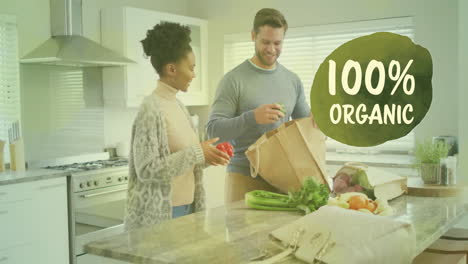 Animation-of-100-percent-organic-text-over-diverse-couple-preparing-healthy-meal-in-kitchen