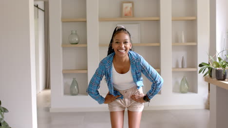 African-American-young-woman-standing,-hands-on-hips,-smiling-at-home