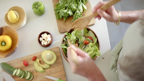 Caucasian-mature-woman-preparing-salad,-adding-vegetables