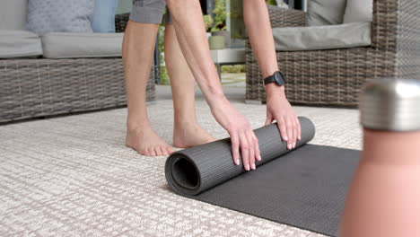 A-person-is-rolling-up-yoga-mat-on-a-patterned-rug-outdoors