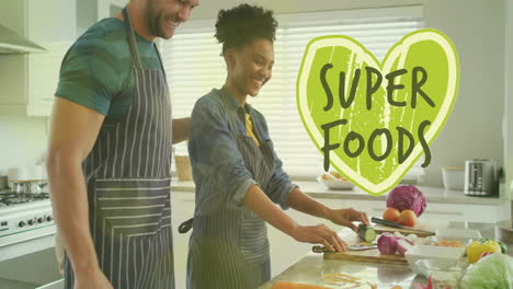 Animation-of-super-foods-text-over-diverse-couple-preparing-healthy-meal-in-kitchen