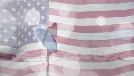 Animation-of-american-flag-and-light-spots-over-caucasian-woman-carrying-surfboard-on-sunny-beach