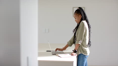 Afroamerikanische-Junge-Frau-Steht-Mit-Laptop-Auf-Weißem-Schreibtisch