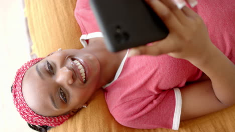 African-American-young-woman-lying-down,-holding-smartphone