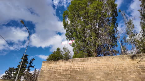 A-section-of-the-old-city-wall-in-Nicosia,-Cyprus,-with-a-tall-tree-and-a-flagpole-visible