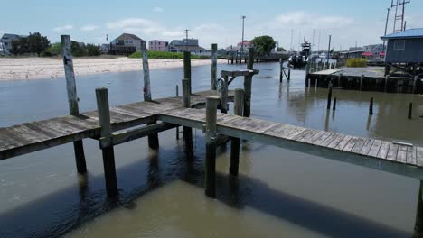 Low-rising-flyover-old-dock-in-canal-in-Bowers-Beach-Delaware-summer-sunny-day-drone