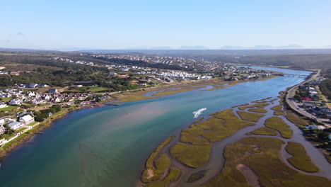 Speedboat-with-water-skier-racing-up-scenic-Goukou-river-in-Stilbaai,-drone-view
