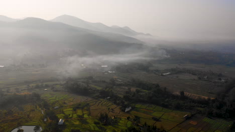 Aerial-view-of-a-gentle-mist-over-farm-fields-in-the-mountains-of-Thailand