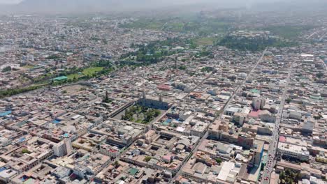 Enjoy-a-stunning-aerial-view-of-Arequipa-from-500-meters-high,-exploring-the-city-until-reaching-the-majestic-square-and-its-cathedral-in-an-exciting-downward-pan
