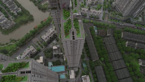 Ascending-aerial-view-of-high-rise-buildings-in-Hanoi,-Vietnam,-adorned-with-lush-greenery-on-rooftops,-embodying-a-modern-urban-jungle-concept