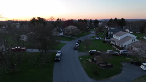 Aerial-view-of-white-car-driving-on-street-in-quaint-neighborhood-of-USA