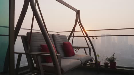 Cozy-Hanging-Swing-Chair-On-The-Balcony-With-A-View-Of-The-City-Skyline