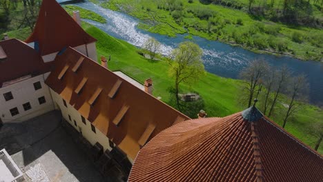 Aerial-establishing-view-of-Bauska-Medieval-Castle-and-ruins,-Musa-and-Memele-rivers-next-to-the-castle,-sunny-spring-day,-medium-drone-shot-moving-forward,-tilt-down