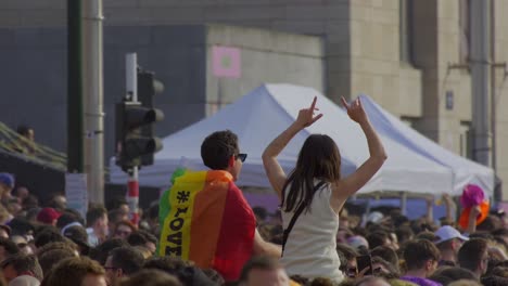 Multitud-En-Un-Festival-Al-Aire-Libre,-Gente-Celebrando-Con-La-Bandera-Del-Arco-Iris