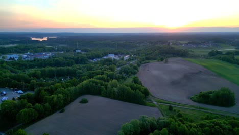 Panorama-at-sunrise,-drone-view-of-the-forest-surrounding-a-small-village